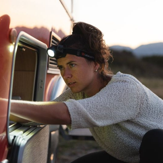 Person using a headlamp near a vehicle in a desert setting