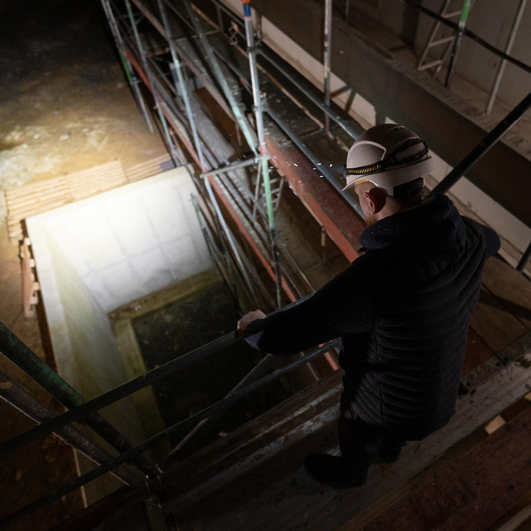 Person on a ladder in a room with exposed ceiling and walls