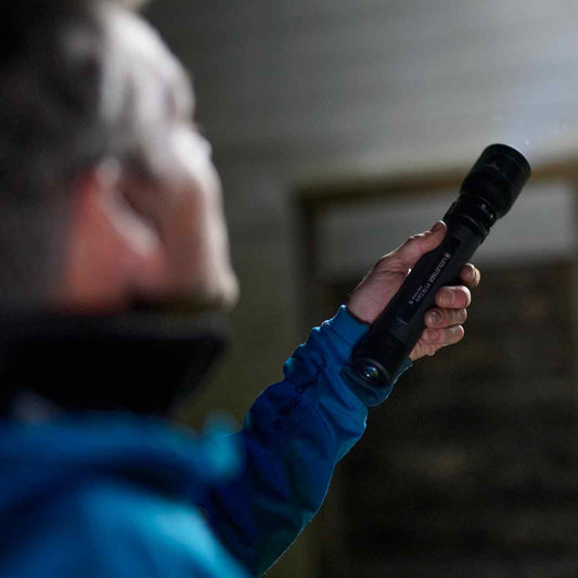 Person holding a flashlight in a dimly lit room