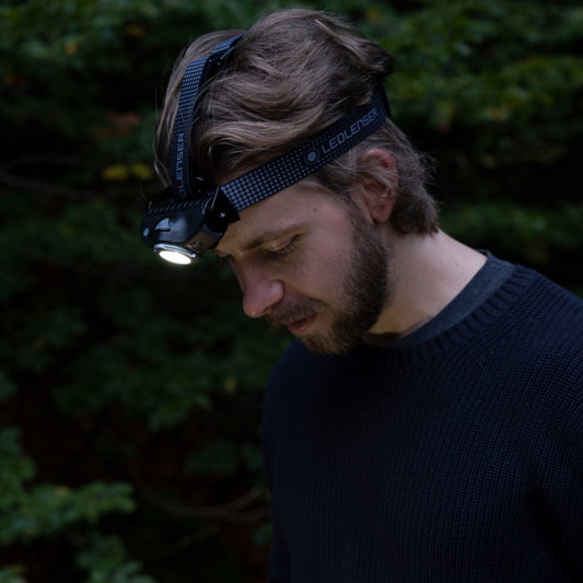 Man wearing a headlamp in a dark outdoor setting