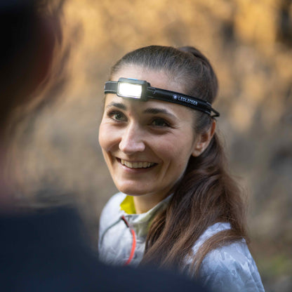 Woman wearing a headlamp in a forest setting