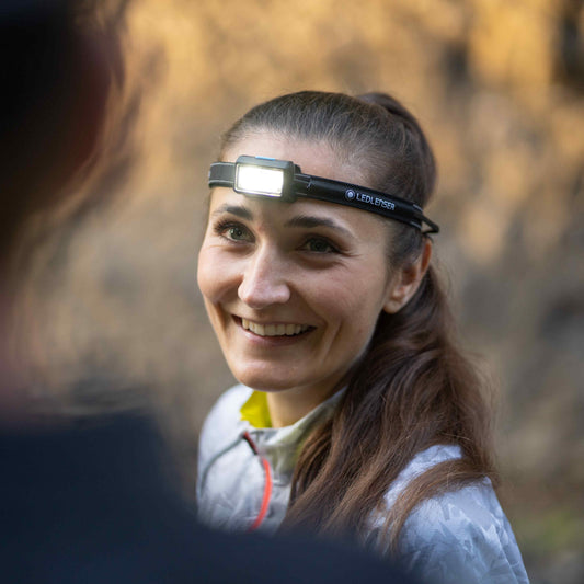 Woman wearing a headlamp in a forest setting