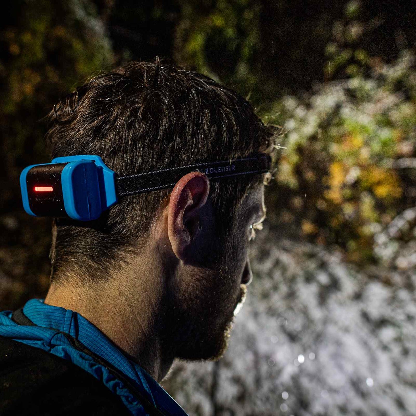 Person wearing a headlamp in a forest setting